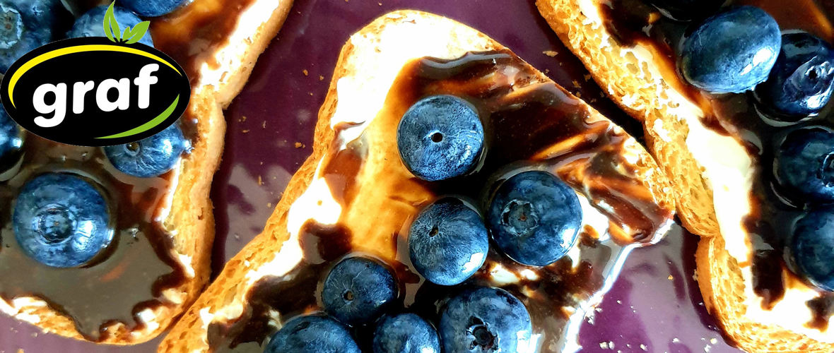 spreaded with carob cream graf and mild cream cheese dried slices of bread with blueberry on the top
